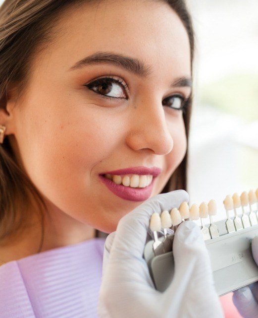 Woman's smile compared with tooth color chart