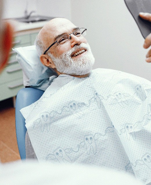 Man smiling at reflection in handheld mirror