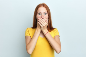 Woman covering her mouth in shock on white background